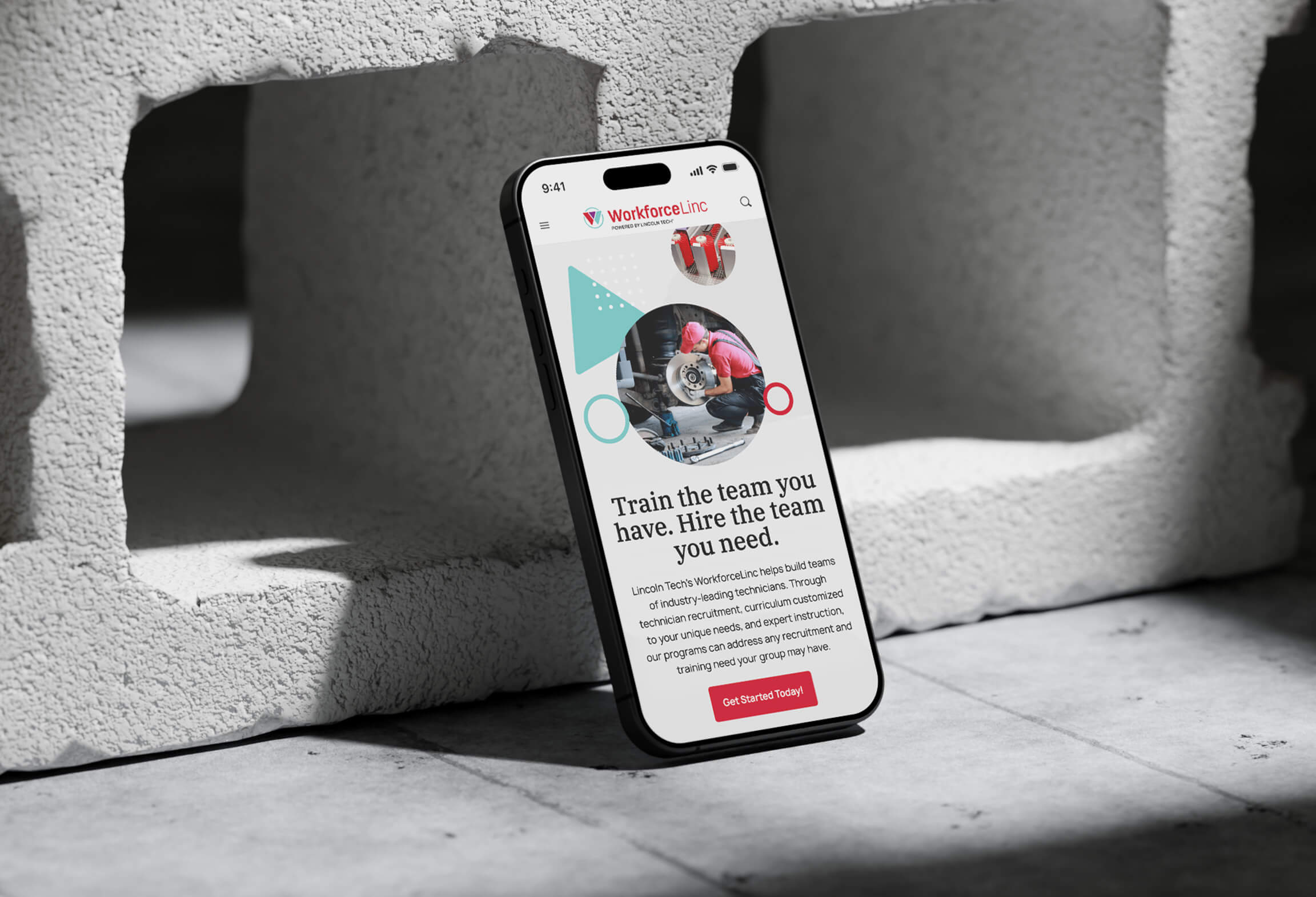 A phone in front of concrete blocks with Lincoln Tech's WorkforceLinc website displayed on the screen