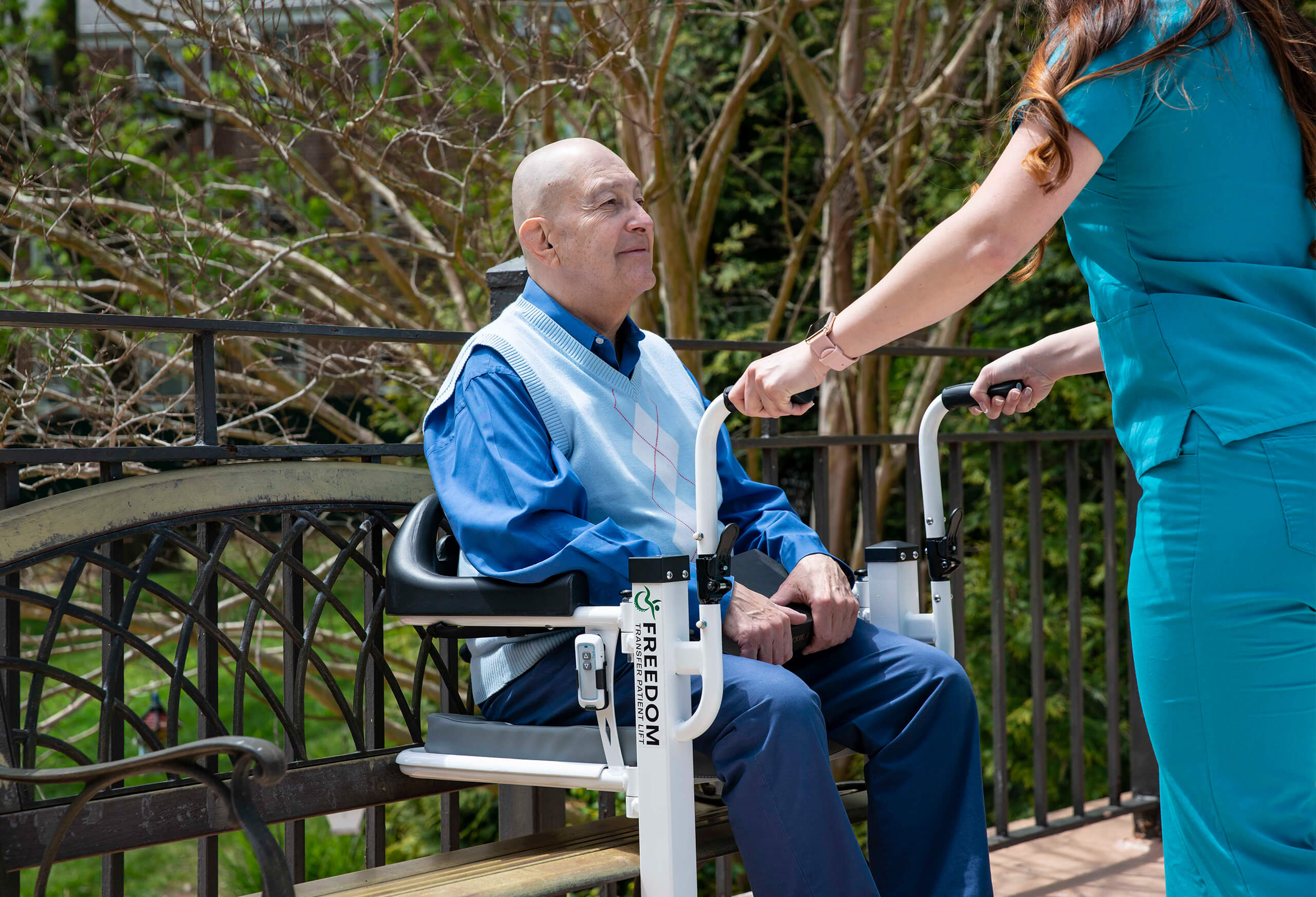Senior caucasian man seated in Mobile PatientLift Freedom Transfer Patient Lift Chair with professional caregiver.