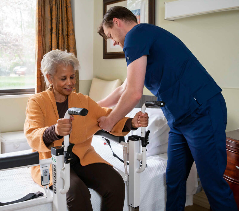 Senior African American woman seated in Mobile PatientLift Freedom Transfer Patient Lift Chair with professional caregiver.