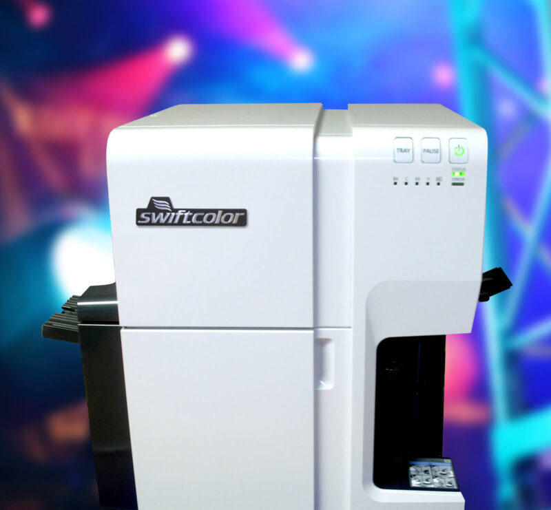 Photo of SwiftColor's SCC-4000D oversized card printer on a colorful background of an event stage